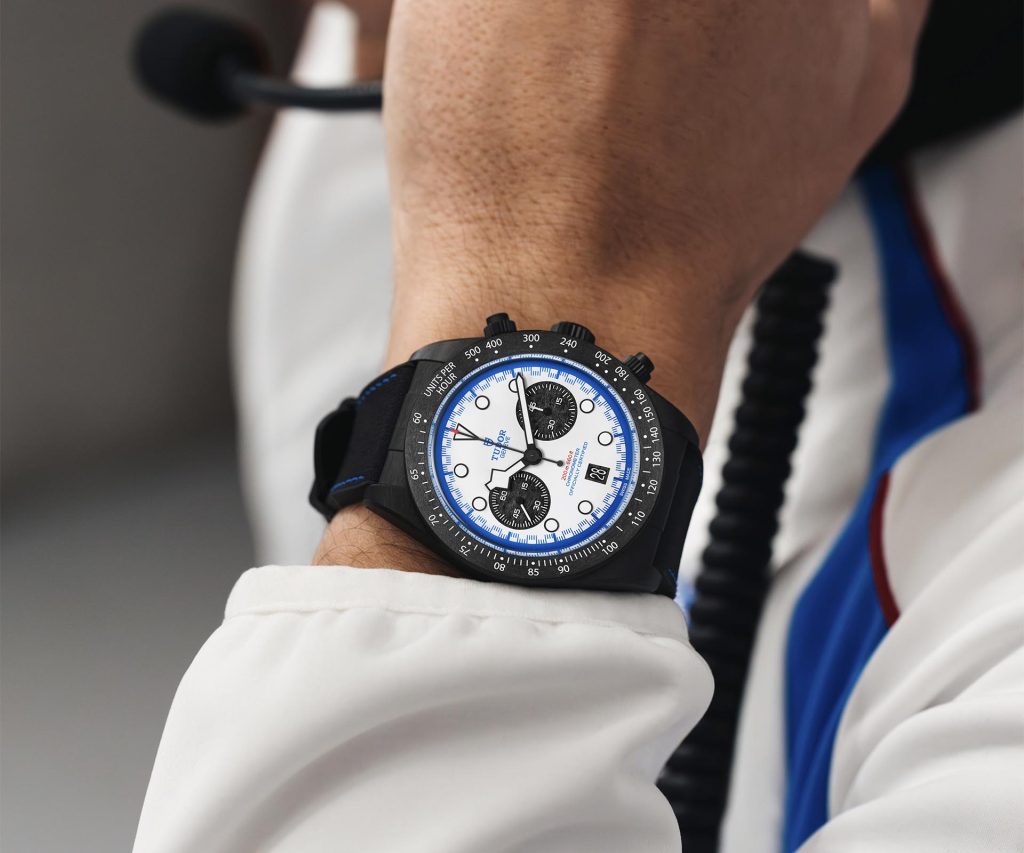 Wrist shot of person wearing TUDOR Black Bay Chrono Carbon 25 with white racing suit
